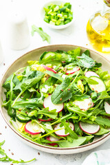 Green salad with spinach, arugula, radish with olive oil and seeds.