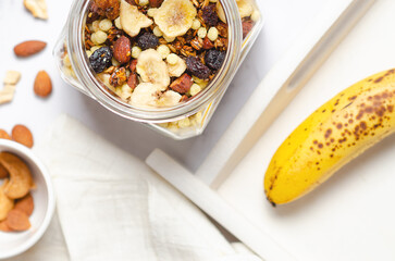 Preparing a healthy breakfast with granola in a glass jar, top view.