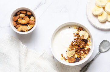 Healthy breakfast with yogurt, granola and nuts on white background.