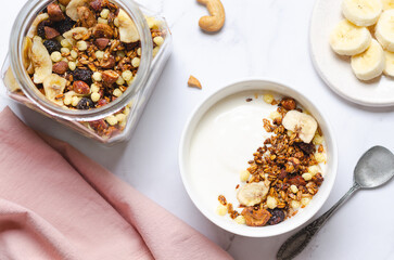 Healthy breakfast - granola with yogurt, nuts and slices of banana, top view.