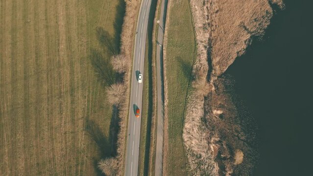 Aerial view of cars driving along highway beside blue water lake