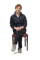 front view of a middle-aged woman sitting on a chair dressed in sportswear with her cross legged on white background © Curto