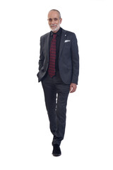 front view of a man walking with suit and tie  looking at camera and hands on pockets on white background