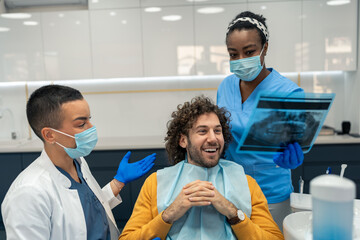 Handsome man with curly hair feeling happy about solved dental problem looking at orthopantomogram...
