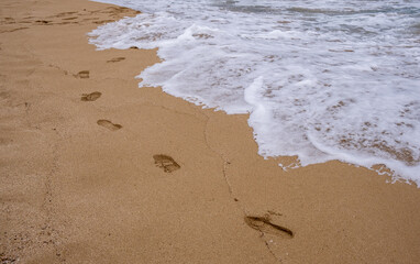 Footprints on a sandy beach and waves on the shore