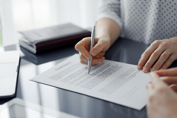 Business people signing contract papers while sitting at the glass table in office, closeup. Partners or lawyers working together at meeting. Teamwork, partnership, success concept