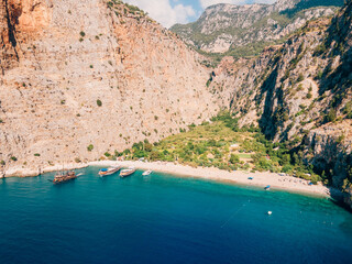 Aerial drone photo capturing the pristine Butterfly Valley in Ölüdeniz, Fethiye, Muğla. This valley is a popular point for tour boats.