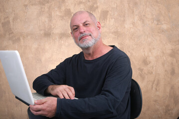 Happy handsome elderly casual man using computer, smiling. Portrait of a middle aged adult, older casual happy smiling, mature aged man with gray hair