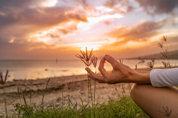 Closeup of hand meditating by the sea at sunset 