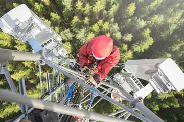 Telecommunication engineer installing 5G LTE antenna on the top of communication tower. Working at...