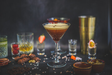 Espresso martini, cocktail shaker, accessories in background, dark backdrop, sophisticated drink, alluring presentation