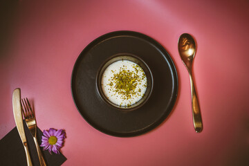 Top view of creamy sutlac, pink background, gold-colored spoon, indulgent Turkish rice pudding,...