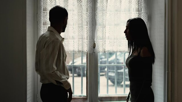 Silhouettes of couple fighting in heated argument. Boyfriend pushing girlfriend with hand. Domestic violence and emotional abuse. Girlfriend slapping man