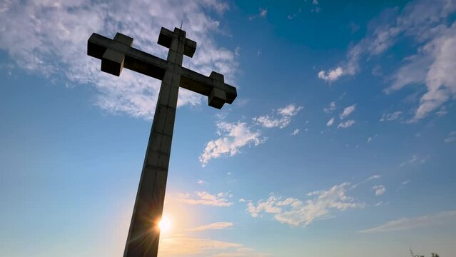 Large stone cross monument on the mountain over Gonio town near Batumi, Georgia at sunset - sun lens flares, low angle. Christianity, religion, spiritual, Orthodoxy, hope and freedom concept