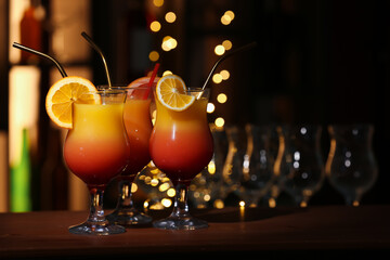 Glasses of tasty Tequila Sunrise with orange slices on table in bar