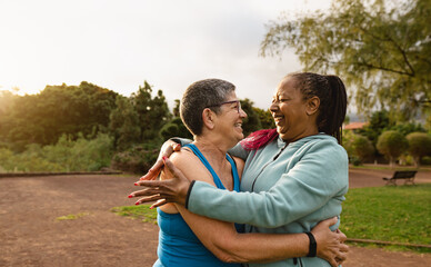 Happy multiracial senior women having fun after workout activities in a public park - Health elderly people concept - 592782485