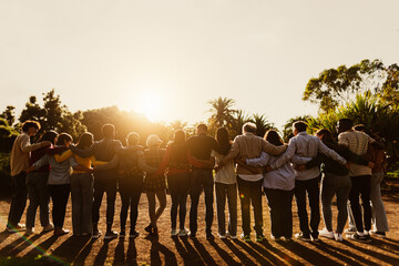 Back view of happy multigenerational people having fun in a public park during sunset time -...