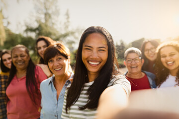 Happy multigenerational group of women with different ethnicities having fun taking selfie with smartphone camera in a public park - Females empowerment concept - 592782498