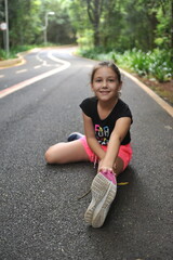 menina se alongando em parque, alongamento para exercicio na natureza 