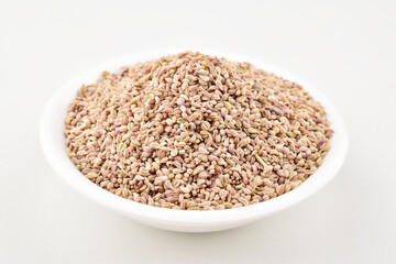 Closeup of ajwain seeds in bowl on white background