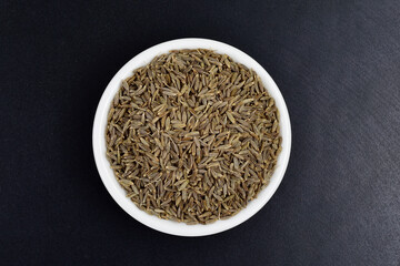 Caraway seeds in bowl on dark background