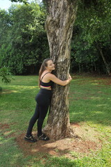 mulher abraçando arvore em parque, conceito de amor a natureza e coneção com o universo 