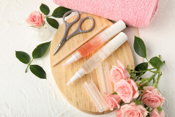 Composition with cuticle oil pens, manicure instruments and rose flowers on light background