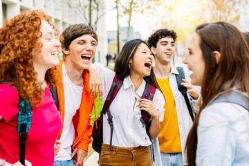 United group of happy multiracial young college friends laughing together outside buildings university campus