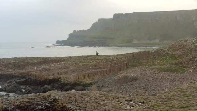 Tourists Exploring Giant's Causeway with Ocean Waves Crashing Against the Rocks