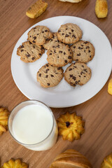 wallpaper of a restaurant table, with a glass of milk next to a plate with chocolate chip cookies, delicious drinks and home baked food, appetizing snack
