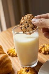 holding a handmade chocolate chip cookie, dipping dessert into a glass of milk, delicious food and drink as wallpaper