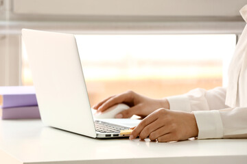Woman using USB flash drive with modern laptop at light table