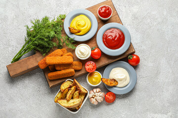 Composition with different sauces, snacks and vegetables on grey grunge table
