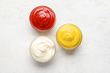Bowls of ketchup, mayonnaise and mustard on white grunge table