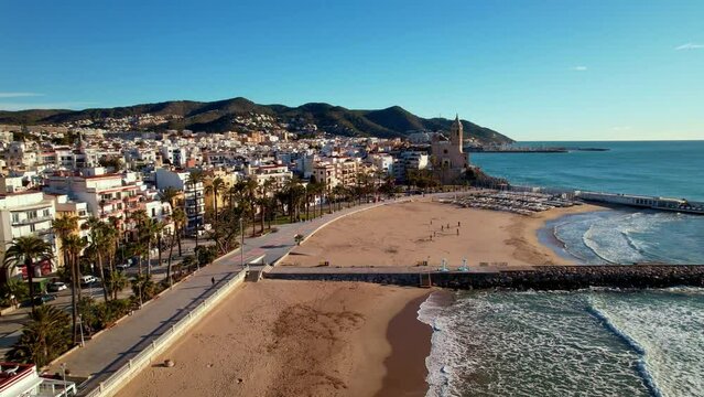 Aerial panoramic view of coastal village, Sant Bartomeu i Santa Tecla de Sitges during sunny day in Sitges, town near Barcelona in Catalonia, Spain. It is famous for its beaches. Film intro. 4K video
