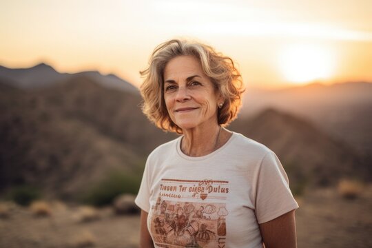 Portrait of happy senior woman looking at camera while standing in desert at sunset