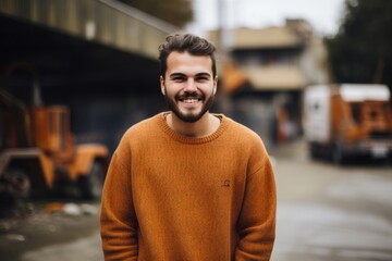 Fototapeta premium Portrait of a handsome young man in an orange sweater standing outdoors