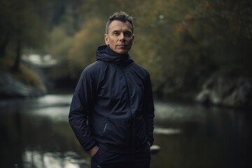 Portrait of a handsome middle-aged man in sportswear standing by the river.