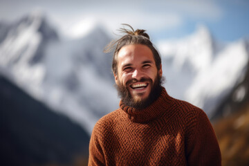 Portrait of a smiling man in a sweater on the background of mountains