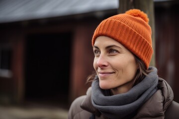 Portrait of a smiling woman wearing a hat and scarf in the countryside