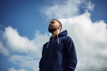 Portrait of a man in a blue hoodie against the sky