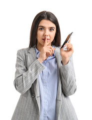 Pretty young woman with smartphone showing silence gesture on white background