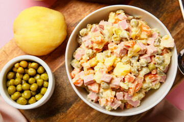Bowl of tasty Olivier salad on pink background, closeup