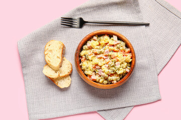 Bowl of tasty Olivier salad and bread on pink background