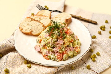Plate of tasty Olivier salad on yellow background
