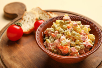 Bowl of tasty Olivier salad on yellow background, closeup