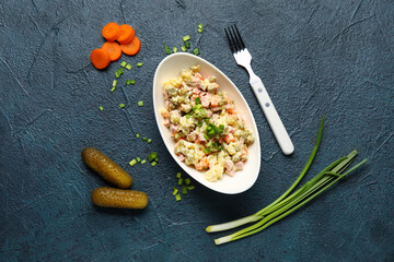 Composition with tasty Olivier salad, carrot and cucumber on dark background