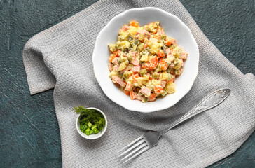 Bowl of tasty Olivier salad on dark background