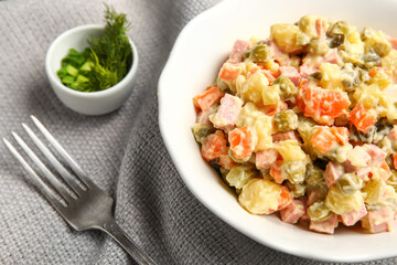 Bowl of tasty Olivier salad on table, closeup