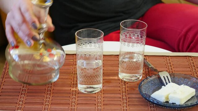 Woman serves raki, a strong drink. When some water is added to pure raki, its color turns white and in Turkish table culture, it is served with a separate glass of cold water and a white cheese plate
